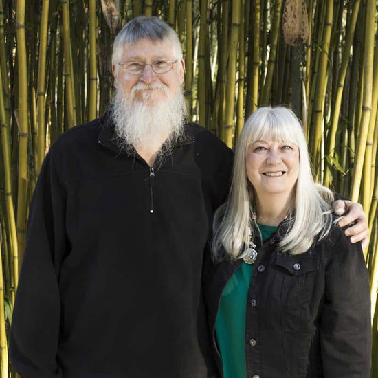Gayle and Roger Lewis, Sr in front of a bamboo grove.